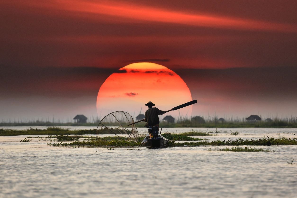 An Asian fisherman doing his job at the sunset