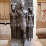 Egyptian statues against a wide pillar
