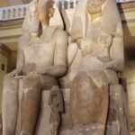two Egyptian statues in museum with balcony in background